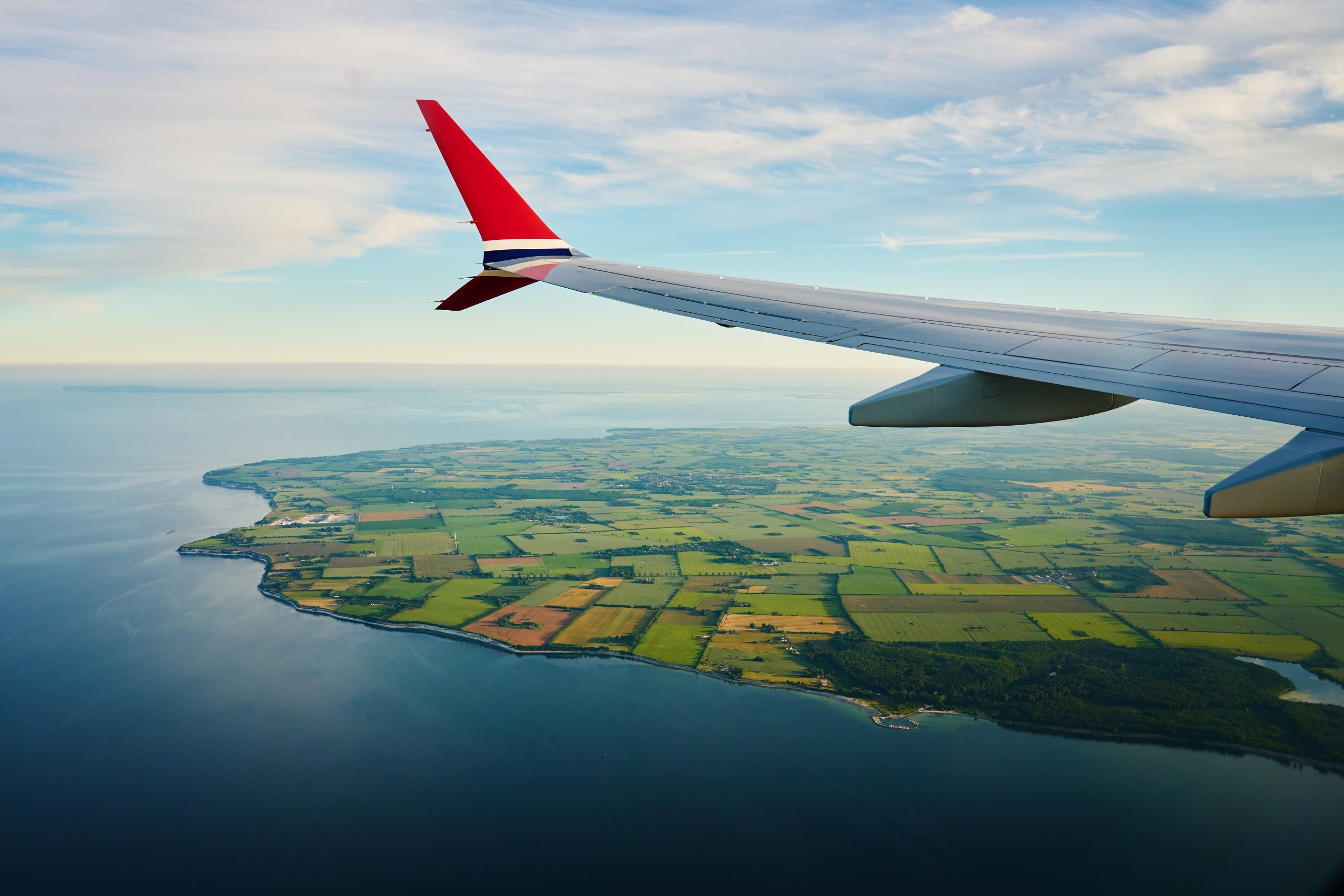 taxed in two countries? Expat Tax guide on being taxed in two countries with the image of a plane wing over lush green scenery